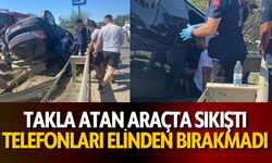 Takla atan araçta sıkıştı, telefonları elinden bırakmadı